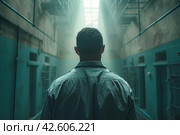 Rear view of a male in gray clothing, facing away from the camera, standing inside a jail cell with light shining through. ,    Generative AI. Стоковое AI-изображение, AI-художник Анна Кривицкая / Фотобанк Лори