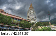 A beautiful ancient seven-tiered pagoda Ban Po Thar against a cloudy sky. Monastery houses among the green vegetation in the foreground. Malaysia. Penang. Kek Lok Si Temple (2023 год). Стоковое фото, фотограф Вера Ивановна Кубарева / Фотобанк Лори