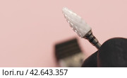 A specialist in gloves holds in his hand a ceramic cutter for hardware manicure with a black notch for removing gel polish with copy space on a pink background. Стоковое видео, видеограф Сергей Чайко / Фотобанк Лори