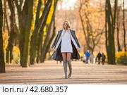 Счастливая молодая женщина гуляет в осеннем парке. По аллее идет привлекательная девушка со светло-каштановыми волосами и в сером пальто. Прекрасное осеннее настроение. Осенний сезон. Стоковое фото, фотограф Андрей Степанов / Фотобанк Лори