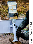 Assembly of fully autonomous, standalone LED street lighting, construction worker install support bracket to wooden pilon. Стоковое фото, фотограф Владимир Григорьев / Фотобанк Лори