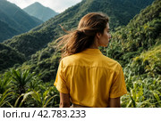 Rear view of lady enjoy at landscape Adam's peak mountain at tropical journey Sri Lanka, Ella, posing. From behind of adult woman in yellow jacket at landmark nature background. Copy ad text space. Стоковое AI-изображение, AI-художник Aleksandr Golubev / Фотобанк Лори