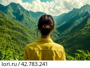 Rear view of lady enjoy at landscape Adam's peak mountain at tropical journey Sri Lanka, Ella, posing. From behind of adult woman in yellow jacket at landmark nature background. Copy ad text space. Стоковое AI-изображение, AI-художник Aleksandr Golubev / Фотобанк Лори