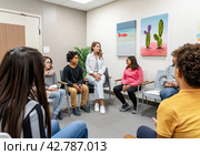 A front view of people attending group therapy, listening attentively to the speaker. Psychotraining. Стоковое AI-изображение, AI-художник Ярославский Максим / Фотобанк Лори