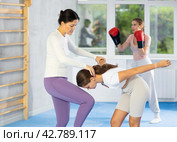 Asian woman performing knee strike to sparring partner face during self-defense training. Стоковое фото, фотограф Яков Филимонов / Фотобанк Лори