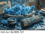 Items that are often associated with meditation, esotericism or relaxation practices. In the center of the frame is a wooden bowl filled with bright blue crystals, likely lapis lazuli stones. To the left of the bowl are bundles of cloth and herbs, similar to resins or smoking sticks, that can be used for space cleansing or aromatherapy. Smoke from the resin floats above the bowl, giving the scene a mystical atmosphere. The background is made up of antique vases and natural wood, which emphasizes the naturalness and traditionality of the scene. Стоковое AI-изображение, AI-художник Анна Кривицкая / Фотобанк Лори