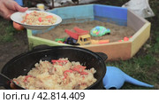 Pilaf is prepared and placed on a plate with a ladle.  Cook rice in a cauldron in the open air in the yard. Стоковое видео, видеограф Дмитрий Кобзев / Фотобанк Лори