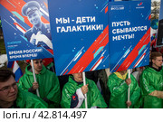 Участники космического шествия держат плакат с портретом Юрия Гагарина в день космонавтики 12 апреля на ВДНХ в городе Москве, Россия (2024 год). Редакционное фото, фотограф Николай Винокуров / Фотобанк Лори