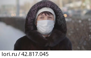 Portrait of middle aged woman wearing protective mask and in a mink fur coat on a city street in winter weather. Quarantine coronavirus covid-19 . Стоковое видео, видеограф EStarodubov / Фотобанк Лори