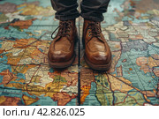 Legs of a man in stylish brown leather lace-up shoes standing on a surface covered with a large map. The map appears to be ancient, with images of lands, bodies of water and names in Latin, done in a traditional style. Стоковое AI-изображение, AI-художник Анна Кривицкая / Фотобанк Лори
