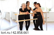 Group of women of various ages, passionate about ballet, friendly chatting while relaxing at barre after intense rehearsal in well-lit dance studio. Стоковое видео, видеограф Яков Филимонов / Фотобанк Лори