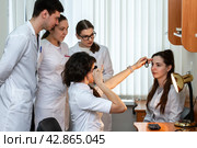 Молодые врачи на обучении проверяют зрение девушки (2022 год). Редакционное фото, фотограф Elena Kotova / Фотобанк Лори