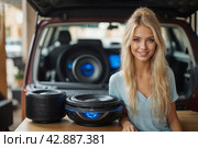 A beautiful blonde girl at an auto sound competition. Car music. Subwoofers, amplifiers, acoustics. Car audio system. Стоковое AI-изображение, AI-художник Александр Поташев / Фотобанк Лори