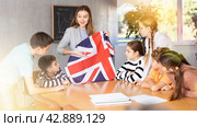 Positive female teacher discussing with preteens students state flag of Great Britain in auditory of middle school. Стоковое фото, фотограф Яков Филимонов / Фотобанк Лори