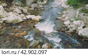 Drone view of mountain river in lush forest. Crystal clear water flows in mountain river, captured from above. Conservation of mountain river ecosystem emphasized in footage (2024 год). Редакционное видео, видеограф ILIA GOROKHOV / Фотобанк Лори