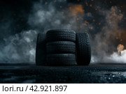 Автомобильные шины в темном дымном помещении, освещенные рисующим светом. Стоковое AI-изображение, AI-художник Максим Коломыченко / Фотобанк Лори