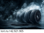 Автомобильные шины с дисками в темном дымном помещении, освещенные рисующим светом. Стоковое AI-изображение, AI-художник Максим Коломыченко / Фотобанк Лори