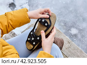 Anti-slip device for winter shoes, spikes on rubber backing, are put on sole to improve traction and prevent slipping in icy conditions. Стоковое фото, фотограф Владимир Григорьев / Фотобанк Лори