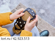 Attaching rubber pad with spikes to sole of shoe will prevent slipping during icy conditions. Стоковое фото, фотограф Владимир Григорьев / Фотобанк Лори
