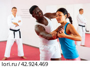 Woman and african american man practice painful grips in self-defense lessons. Стоковое фото, фотограф Яков Филимонов / Фотобанк Лори