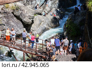 ARSHAN VILLAGE, TUNKINSKIY DISTRICT, BURYATIA, RUSSIA -  August 12, 2023: Many tourists come along Eco Health Path to waterfall on mountain river Kyngarga to take pictures in Tunkinskiy Park reserve. Редакционное фото, фотограф Виктория Катьянова / Фотобанк Лори