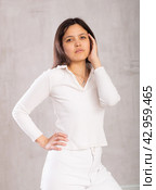Dark-haired model put one hand on waist and coquettishly holds unfastened hair with handbreadth. Стоковое фото, фотограф Яков Филимонов / Фотобанк Лори