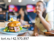 A woman is eating a burger in a restaurant. Стоковое фото, фотограф Константин Шишкин / Фотобанк Лори