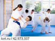 Teen girl honing grappling techniques during kumite with boy at karate training. Стоковое фото, фотограф Яков Филимонов / Фотобанк Лори