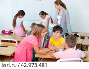 Concentrated preteen girls and boys solving teacher assignments in groups. Стоковое фото, фотограф Яков Филимонов / Фотобанк Лори