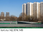 Многоэтажные панельные жилые дома. На переднем плане крыши гаражей. Вдали строительство высотных зданий. Жилые кварталы в спальном районе большого города. Городские окраины. Стоковое фото, фотограф Андрей Степанов / Фотобанк Лори