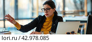 A woman in the office at a desk with a laptop asks to wait, giving a hand sign. Стоковое AI-изображение, AI-художник Ярославский Максим / Фотобанк Лори