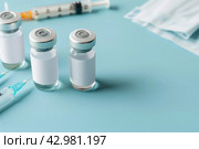 Syringe and glass vial on blue background table. Medical Vials group, needles, ampoules, bottle with medicines or vaccine. Disease treatment. Creative Banner. Anti-aging beauty injections. Vaccination. Стоковое AI-изображение, AI-художник Марина Демидюк / Фотобанк Лори