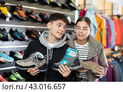 Couple examine view several item of winter comfortable trecking shoes. Стоковое фото, фотограф Яков Филимонов / Фотобанк Лори