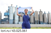 Smiling young woman worker posing with Argentina flag in hands against background of factory. Стоковое видео, видеограф Яков Филимонов / Фотобанк Лори