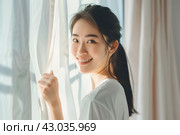 Young asian woman unveil curtain and looking out of window in the morning. Beautiful girl nearly window after waking up fully rested and open curtains. Start the new day with happiness. Relax, resting. Стоковое AI-изображение, AI-художник Марина Демидюк / Фотобанк Лори