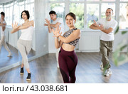 Young girl and group of positive people practicing energetic lindy hop movements at dance school. Стоковое фото, фотограф Яков Филимонов / Фотобанк Лори