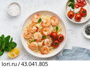 Pasta bavette with fried shrimps, bechamel sauce, mint leaf, garlic, on white plate, top view. Стоковое фото, фотограф Natalia Gdovskaia / Фотобанк Лори