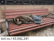 Бездомный, бомж спит на уличной скамейке в Москве (2016 год)/ A homeless man sleeps on a bench on the street in the center of Moscow. Редакционное фото, фотограф Iva Noel / Фотобанк Лори