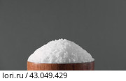 White table salt granules falling into a pile. Wood bowl. Gray color studio background. Condiment particles dropping. Clean cosmetic bath salt pouring footage. Closeup of grained sea salt pieces hill. Стоковое видео, видеограф Марина Демидюк / Фотобанк Лори
