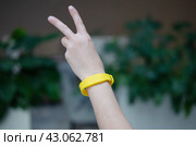 Женские руки с желтым RFID браслетом. Функциональный гаджет для регистрации туристов. Водонепроницаемый бесконтактный силиконовый браслет-ключ доступа с чипом. Стоковое фото, фотограф Дорощенко Элла / Фотобанк Лори