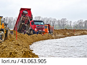 Ливень мешает отсыпке защитной дамбы вдоль дороги.  Разлив реки Тобол в время половодья 2024 года. Тюменская область. Стоковое фото, фотограф Александр Тараканов / Фотобанк Лори