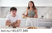 Upset young man sitting at the kitchen-table with his back to his wife disputing with him. Стоковое видео, видеограф Яков Филимонов / Фотобанк Лори