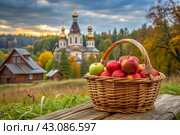The concept of the Russian Orthodox holiday yablochny spas. A beautiful wicker basket made of vines with red ripe apples on the background of an Orthodox church. Стоковое AI-изображение, AI-художник Photojuli / Фотобанк Лори