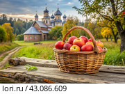 The concept of the Russian Orthodox holiday yablochny spas. A beautiful wicker basket made of vines with red ripe apples on the background of an Orthodox church. Стоковое AI-изображение, AI-художник Photojuli / Фотобанк Лори