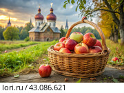 The concept of the Russian Orthodox holiday yablochny spas. A beautiful wicker basket made of vines with red ripe apples on the background of an Orthodox church. Стоковое AI-изображение, AI-художник Photojuli / Фотобанк Лори