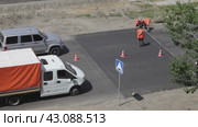 ANGARSK, IRKUTSK REGION, RUSSIA - July 29, 2023: Video of team of road workers in orange signal vests apply markings to Speed Bump or Sleeping policeman on asphalt road. Seasonal work on city roads. Редакционное видео, видеограф Виктория Катьянова / Фотобанк Лори