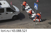 ANGARSK, IRKUTSK REGION, RUSSIA - July 29, 2023: Video of team of road workers in orange vests marking speed bump with white paint in form of signal squares on summer day. Sesonal road works. Редакционное видео, видеограф Виктория Катьянова / Фотобанк Лори