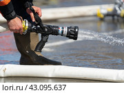 Closeup view of hands of Firefighter Emercom of Russia holding fire hose with automatic double pressure nozzles and pouring water from firehose (2019 год). Редакционное фото, фотограф А. А. Пирагис / Фотобанк Лори