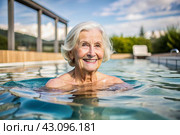 An elderly woman swims and does water aerobics in a heated pool, a happy and smiling retired woman. Recreational water sports. Стоковое AI-изображение, AI-художник Photojuli / Фотобанк Лори