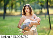 Public breastfeeding by mother with child in city garden. Стоковое фото, фотограф Владимир Григорьев / Фотобанк Лори